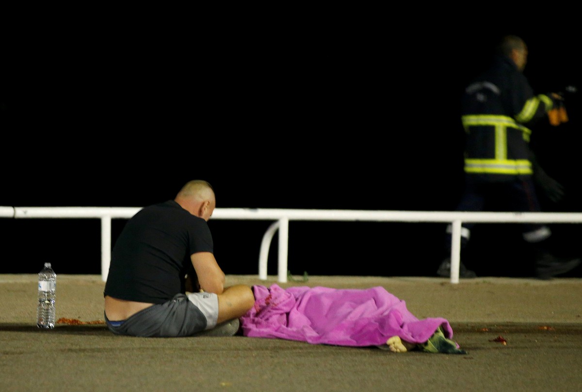 Một người đàn ông như chết lặng bên cạnh thi thể người thân của mình sau vụ tông xe quá kinh hoàng - Ảnh: REUTERS