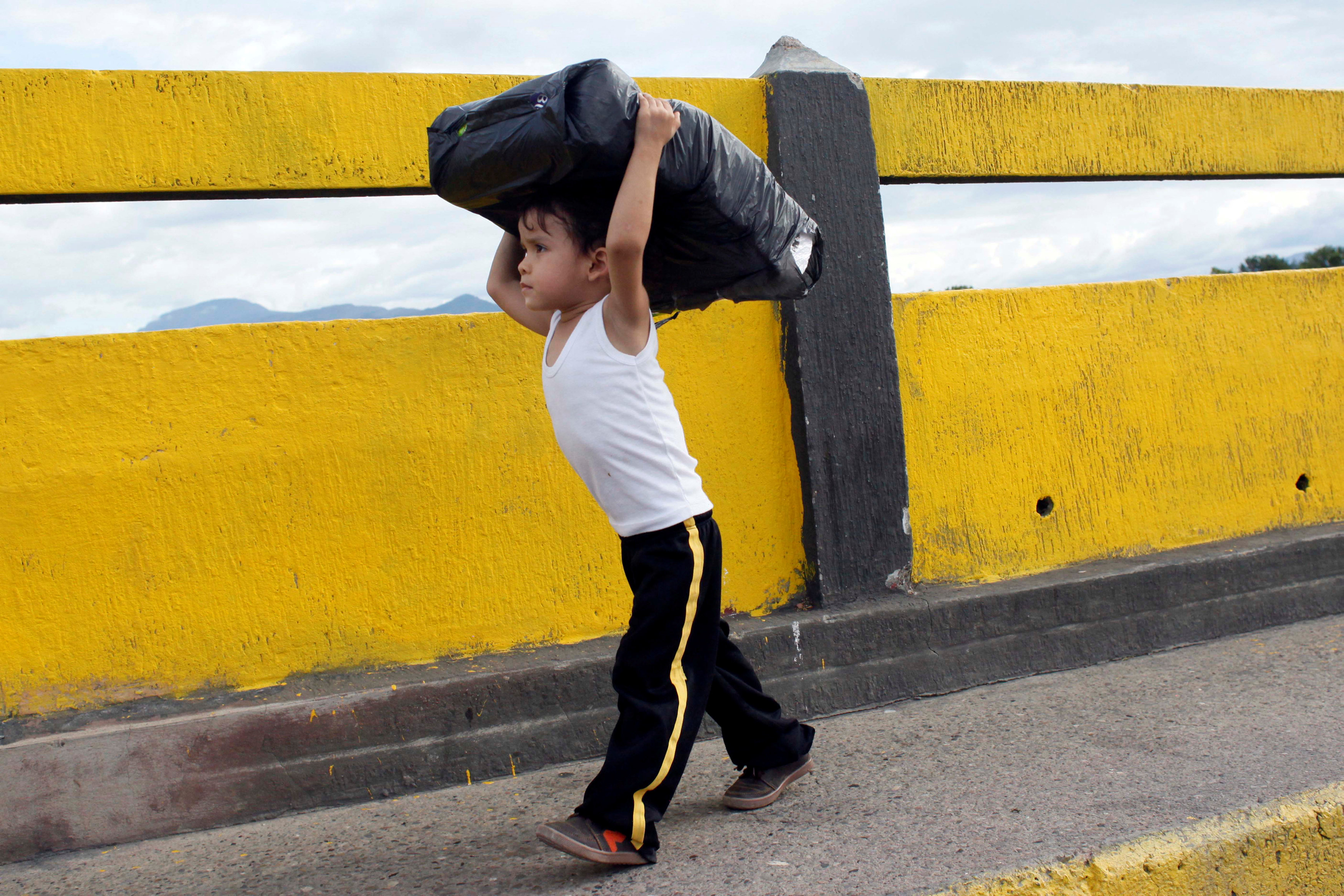 Cậu bé này khuân hàng từ Colombia về Venezuela qua cầu quốc tế Simon Bolivar ở San Antonio del Tachira , VenezuelaSan - Ảnh: REUTERS