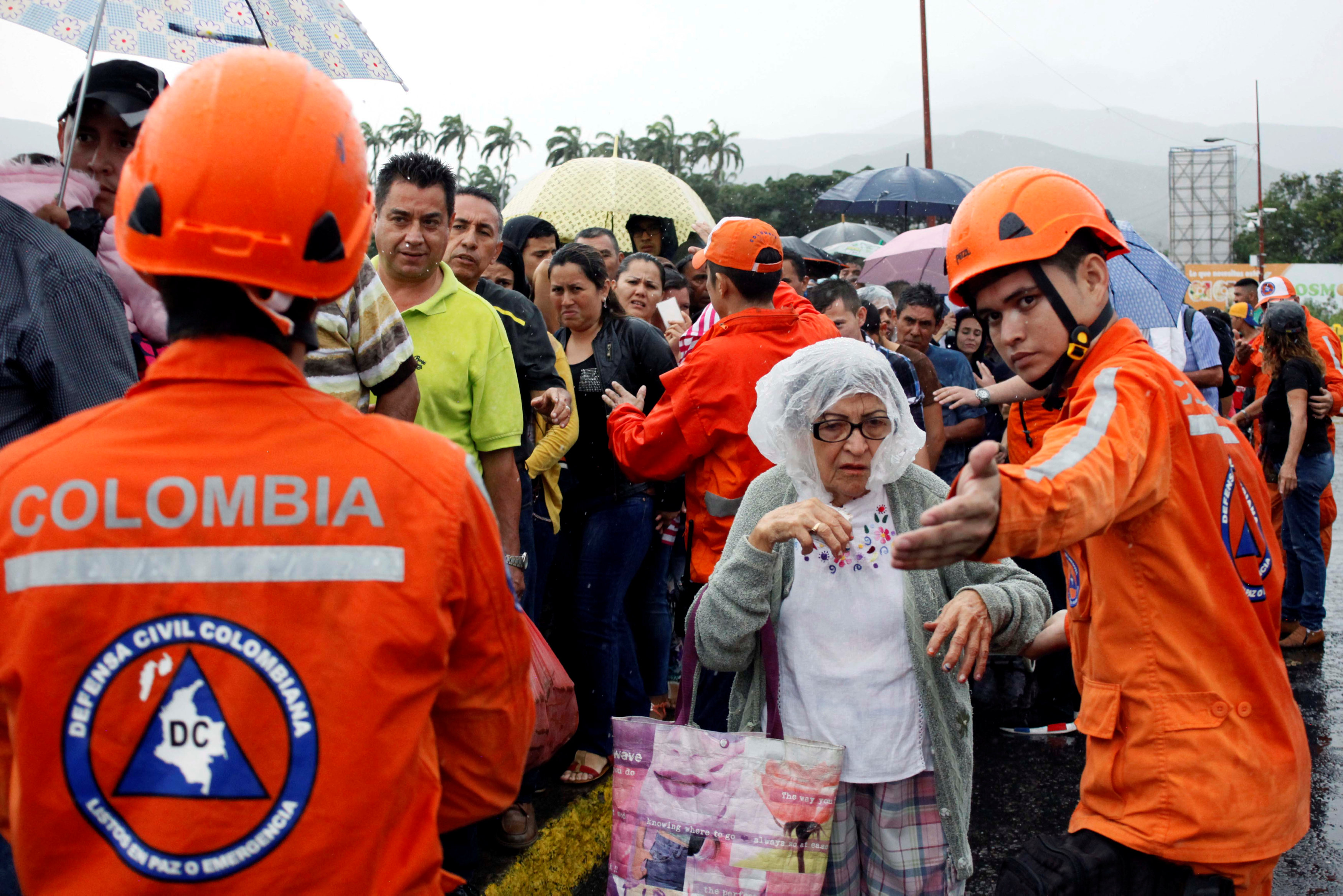 Một cụ bà được lựng lượng tình nguyện Colombia hướng dẫn xếp hàng khi qua biên giới nước này mua hàng - Ảnh: REUTERS