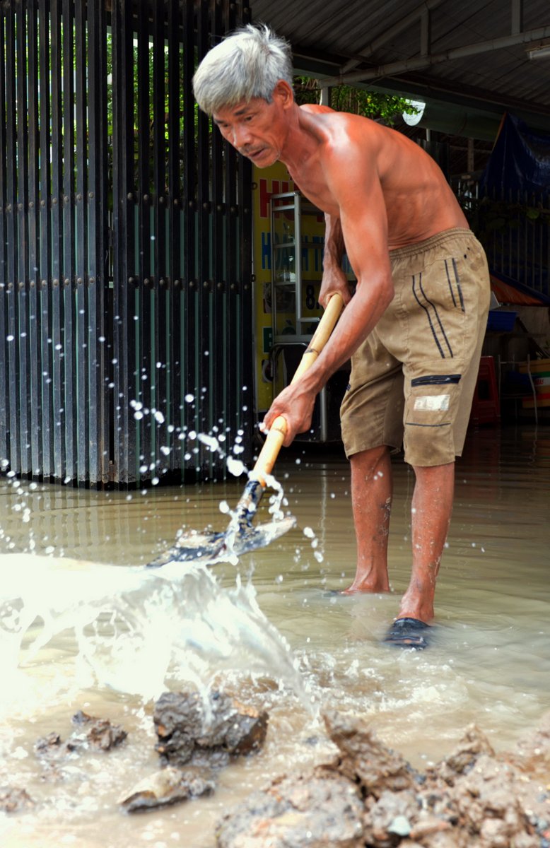 Nước tràn vô nhà dân, một người đàn ông phải khơi thông dòng chảy để nước rút khỏi nhà