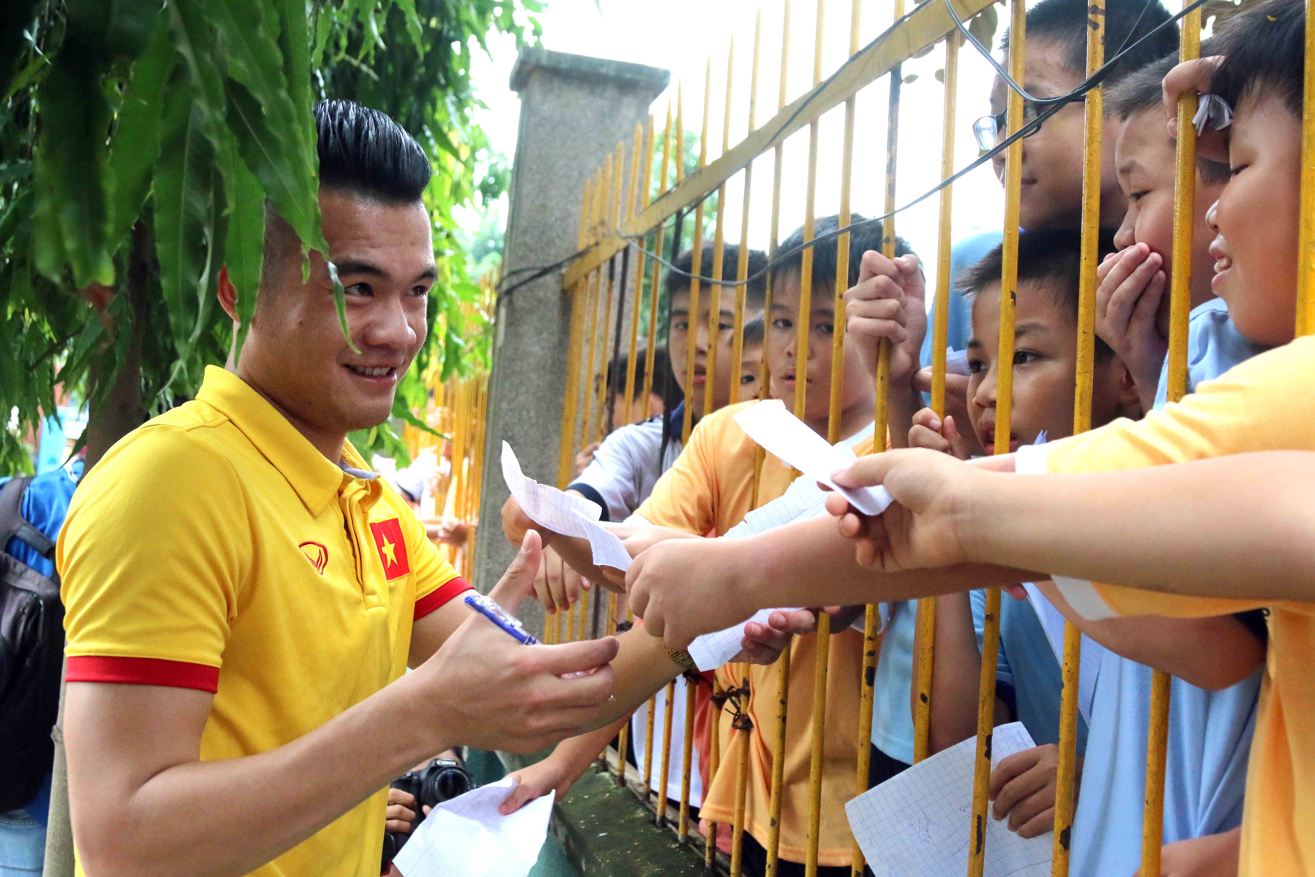 Không chỉ các em ở làng trẻ em SOS Gò Vấp, mà các em học sinh ở ngôi trường bên cạnh cũng với tay qua hàng rào để xin chữ ký Hoàng Thịnh. Ảnh: N.K