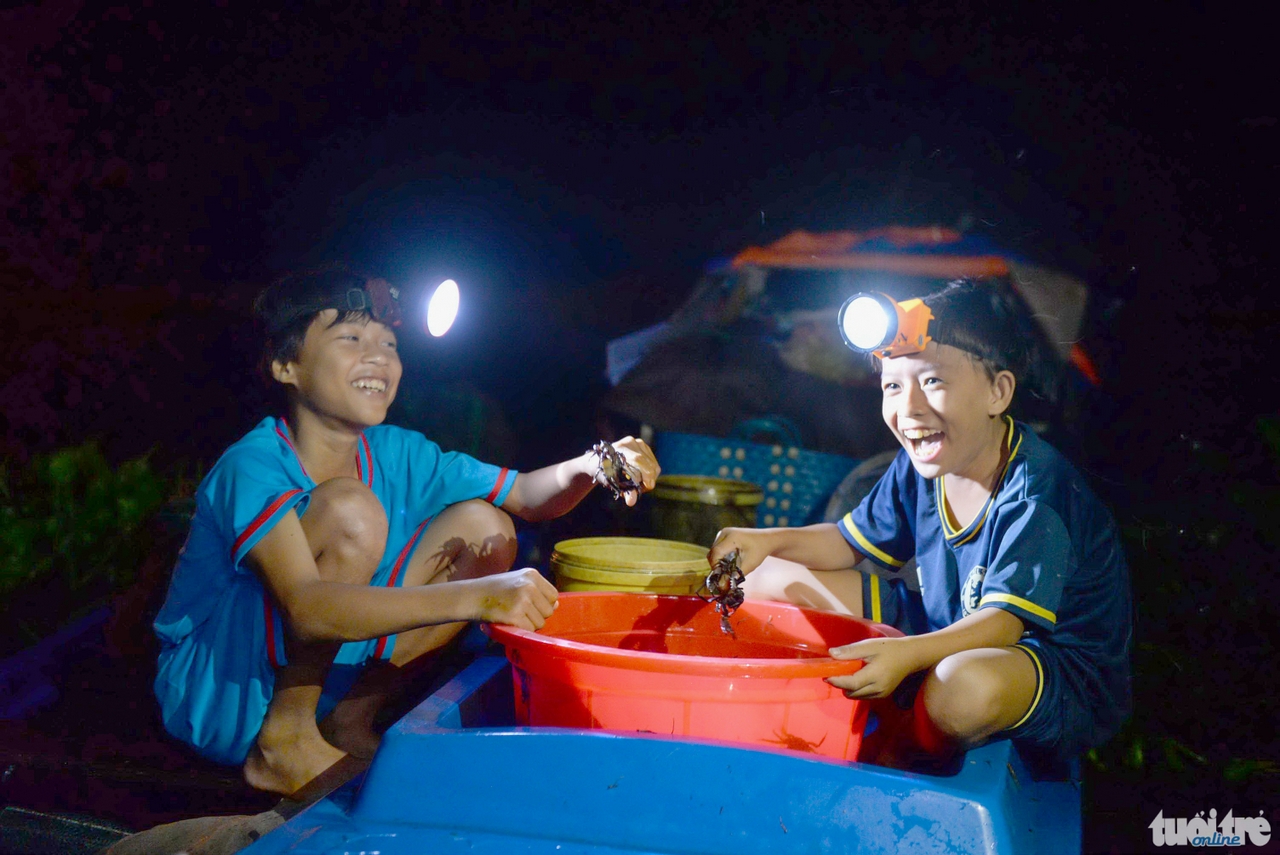 Hai anh em Phạm Văn Duy (15 tuổi) và Phạm Văn Bi (12 tuổi) phụ cha mẹ phân loại cua bán cho thương lái - Ảnh: Hữu Khoa