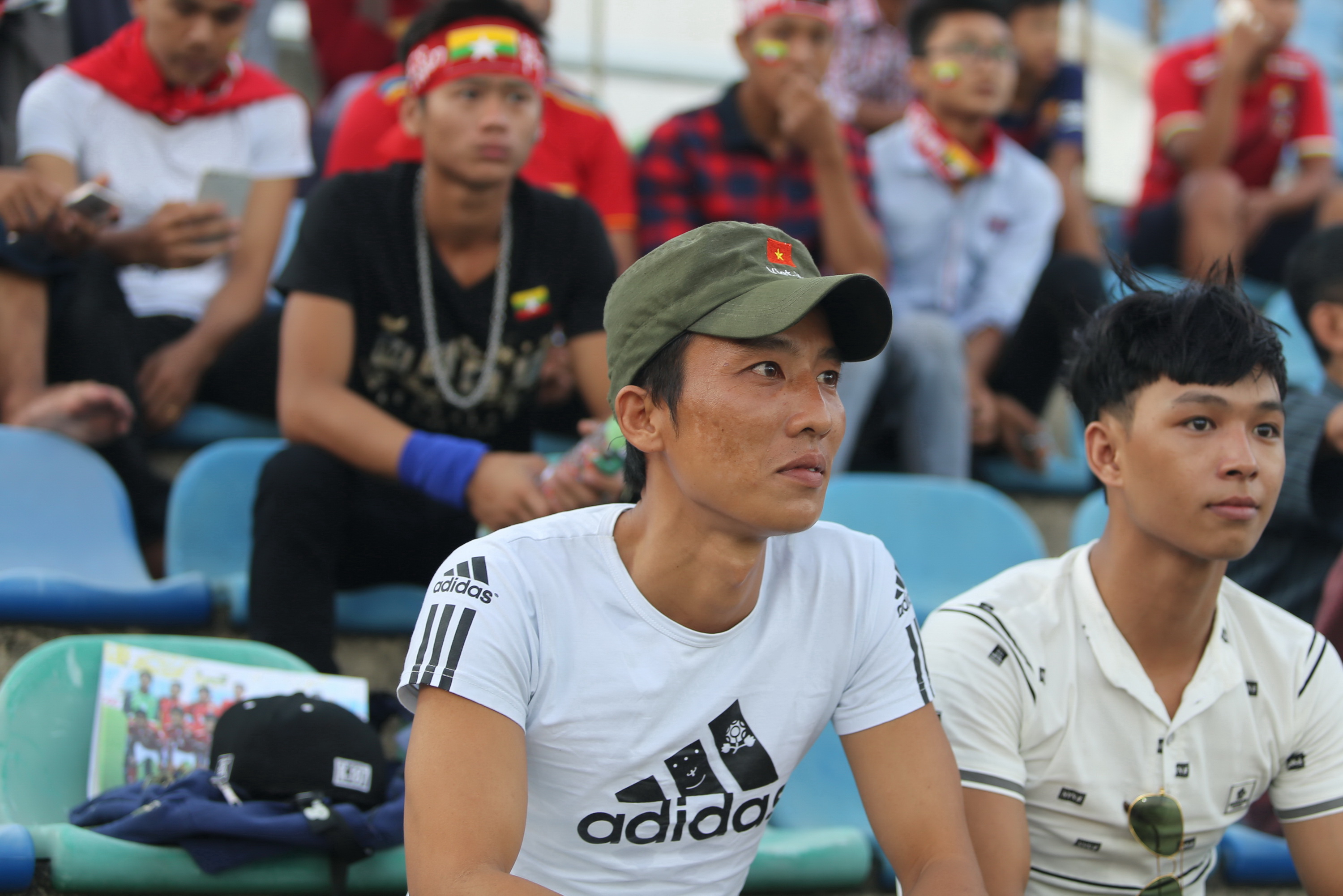 Anh Cần Phước (trái) chỉ dám đội một chiếc mũ in cờ VN nhỏ trong khu vực dành cho CĐV Myanmar trước trận. Ảnh: H.Đ.