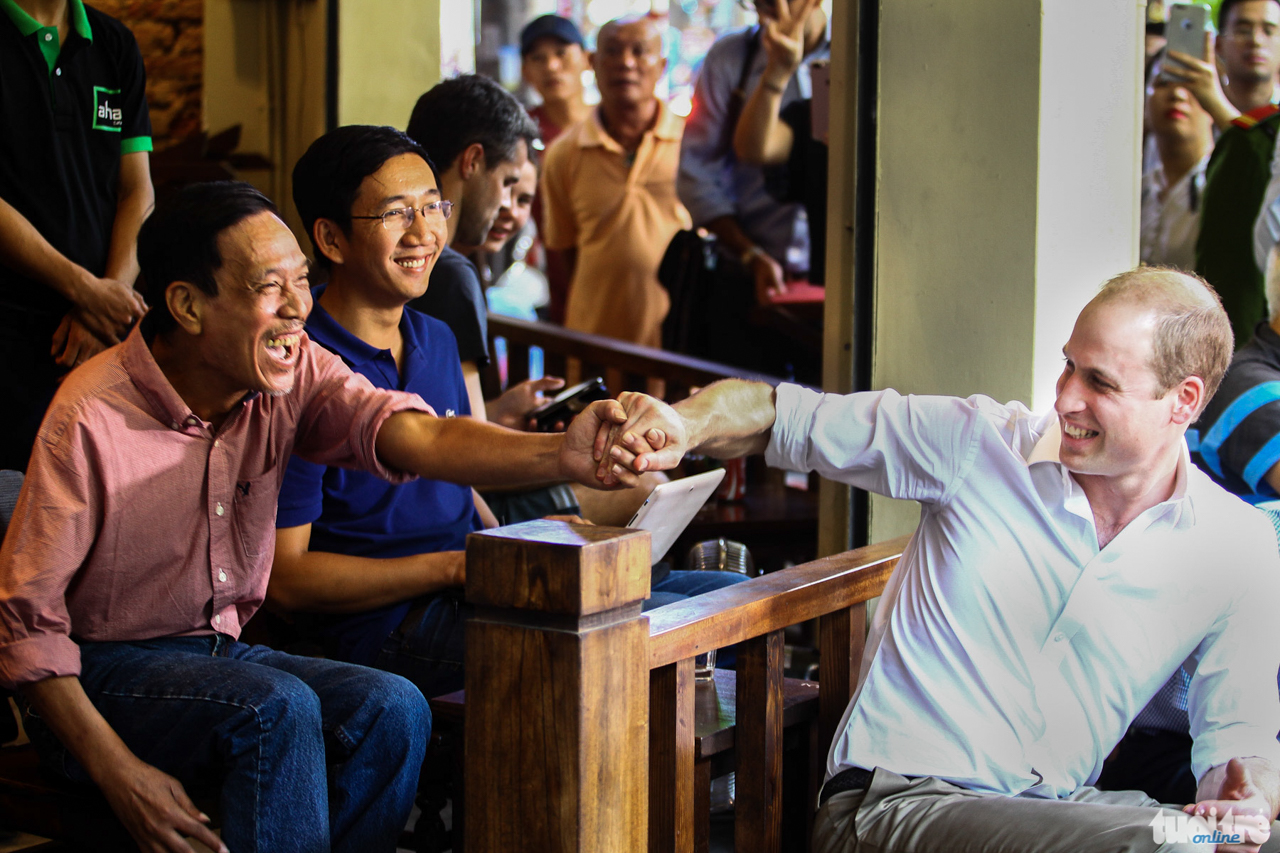 Hoàng tử Anh William thân thiện bắt tay với một người dân khi đang uống cafe tại Phố cổ Hà Nội. Người thừa kế ngai vàng của nước Anh đến Việt Nam để tham dự một Hội nghị quốc tế về buôn bán động thực vật hoang dã bất hợp pháp - Ảnh: NGUYỄN KHÁNH
