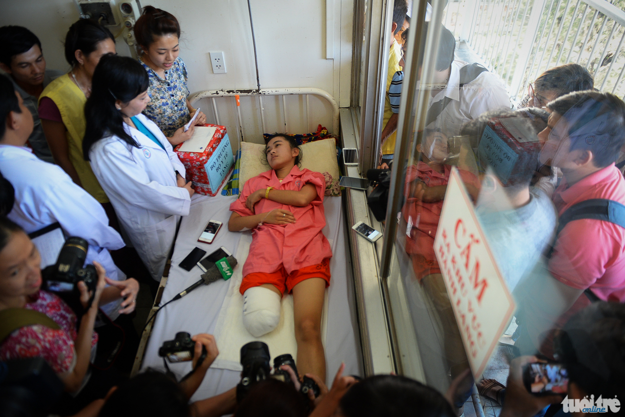  Bộ trưởng Bộ Y tế Nguyễn Thị Kim Tiến cùng người dân đứng quanh em Lê Thị Hà Vi - cô học trò xinh xắn bị cưu nhầm chân do tắc trách của bệnh viện - Ảnh: HỮU KHOA
