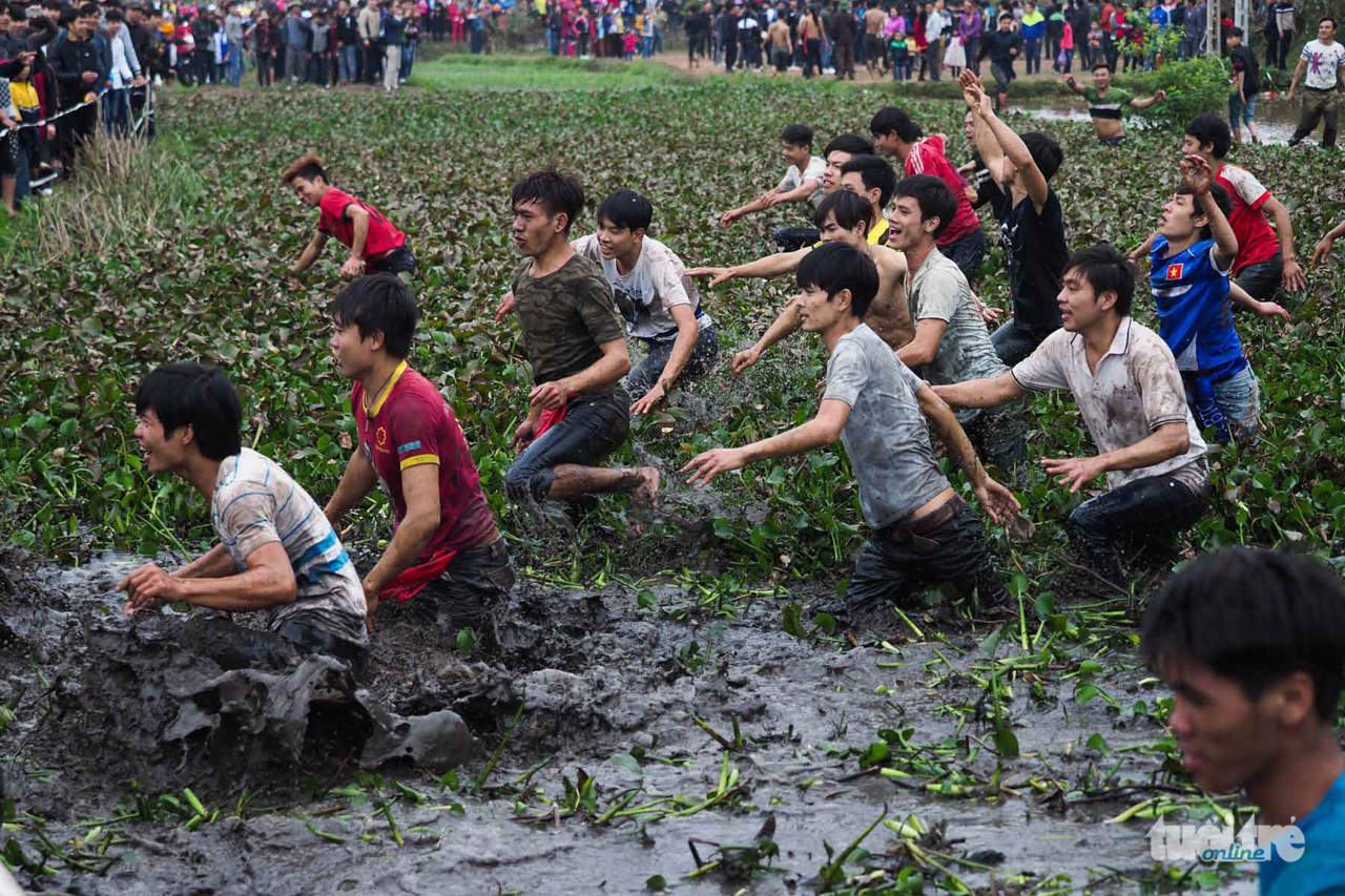 Nhiều thanh niên vượt qua một bãi sình lầy để nhảy vào bãi phết - Ảnh: NGUYỄN KHÁNH
