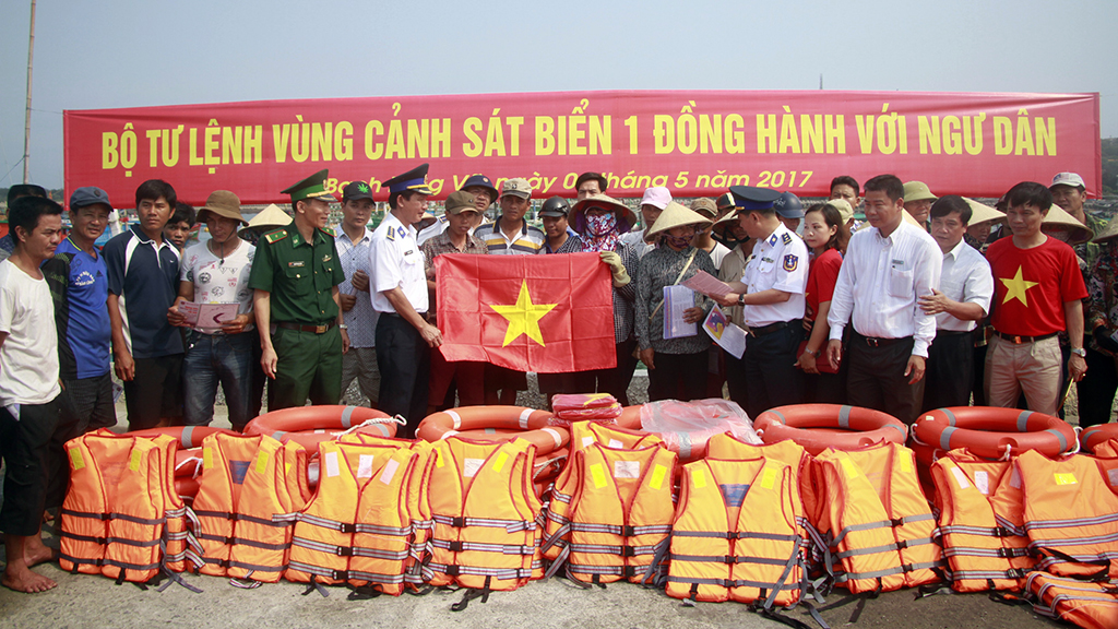 Đại diện BTL Vùng Cảnh sát biển trao tặng áo phao, phao cứu sinh, cờ Tổ quốc… cho ngư dân trên đảo - Ảnh: Đức Hiếu