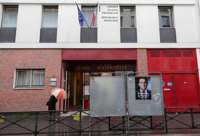 Chân dung ứng viên Macron tại một điểm bầu ngày 7-5 ở Paris, thời điểm này Paris đang có mưa - Ảnh: Reuters