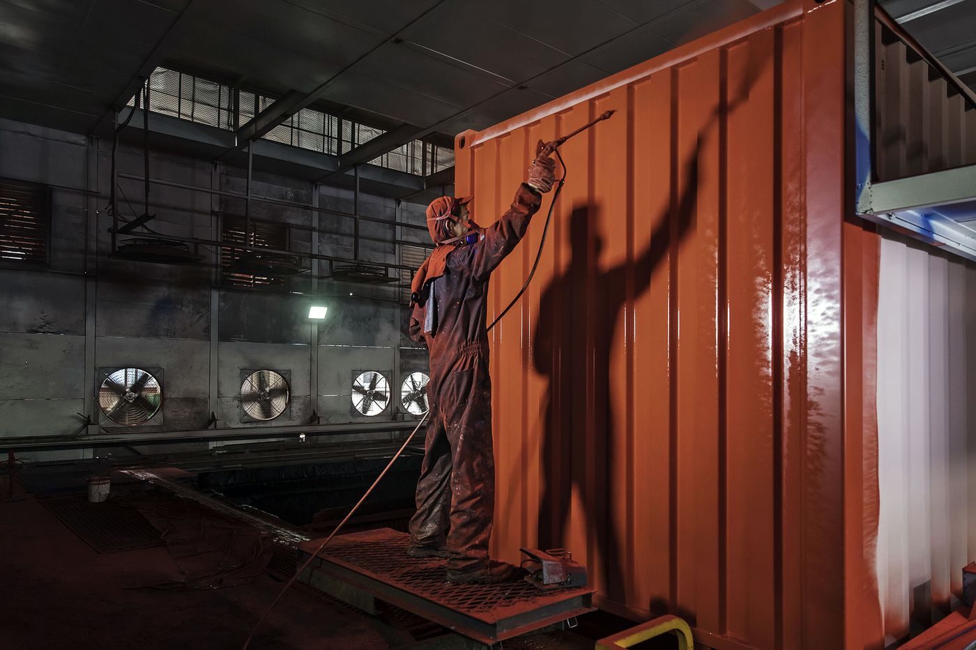 Một công nhân nhà máy Trung Quốc đang sơn thùng công ten nơ - ảnh: QILAI SHEN/BLOOMBERG