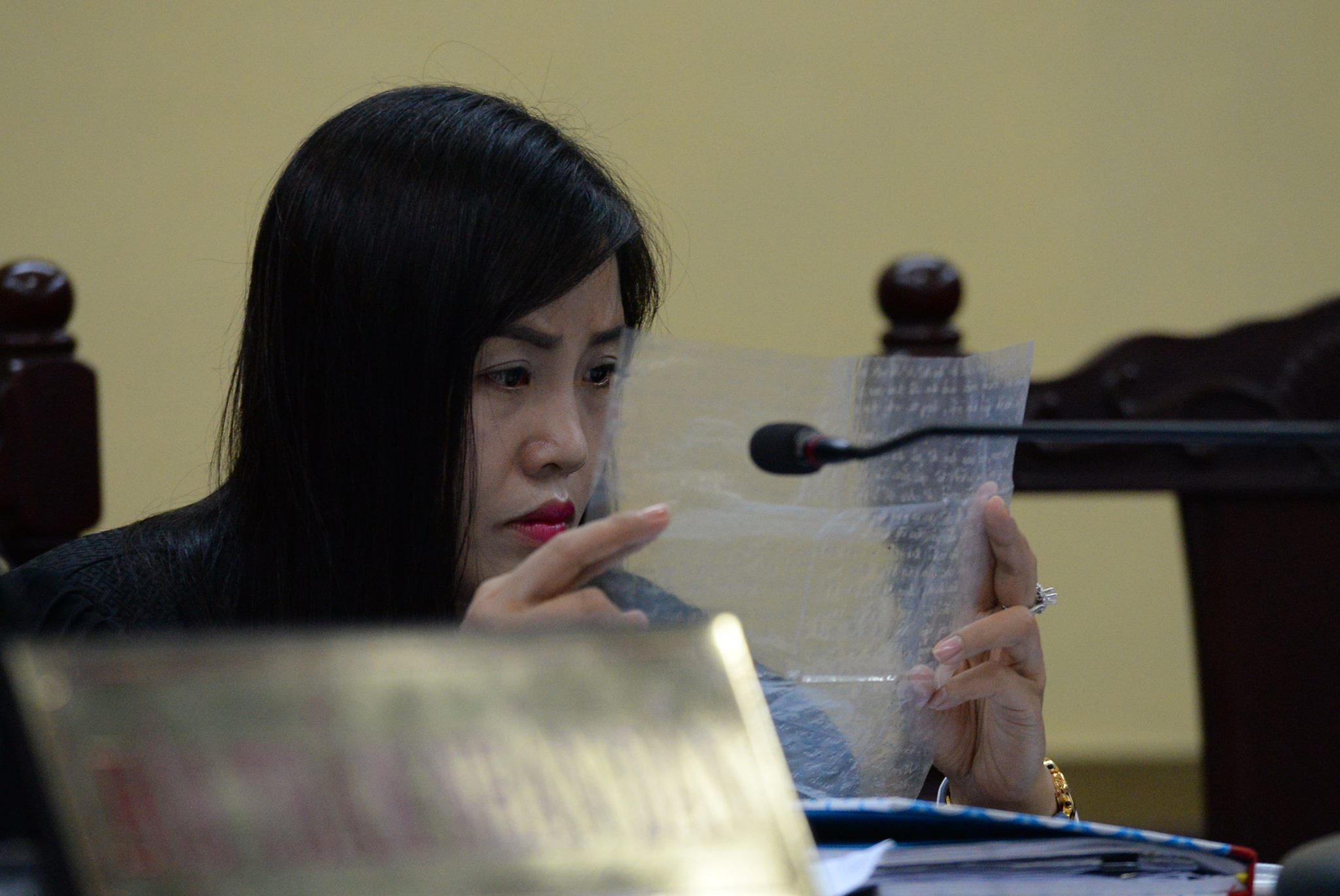 Thành viên hội đồng xét xử xem bức thư viết trên giấy nilon mà Lữ Minh Nghĩa trình cho tòa - Ảnh: Hữu Khoa