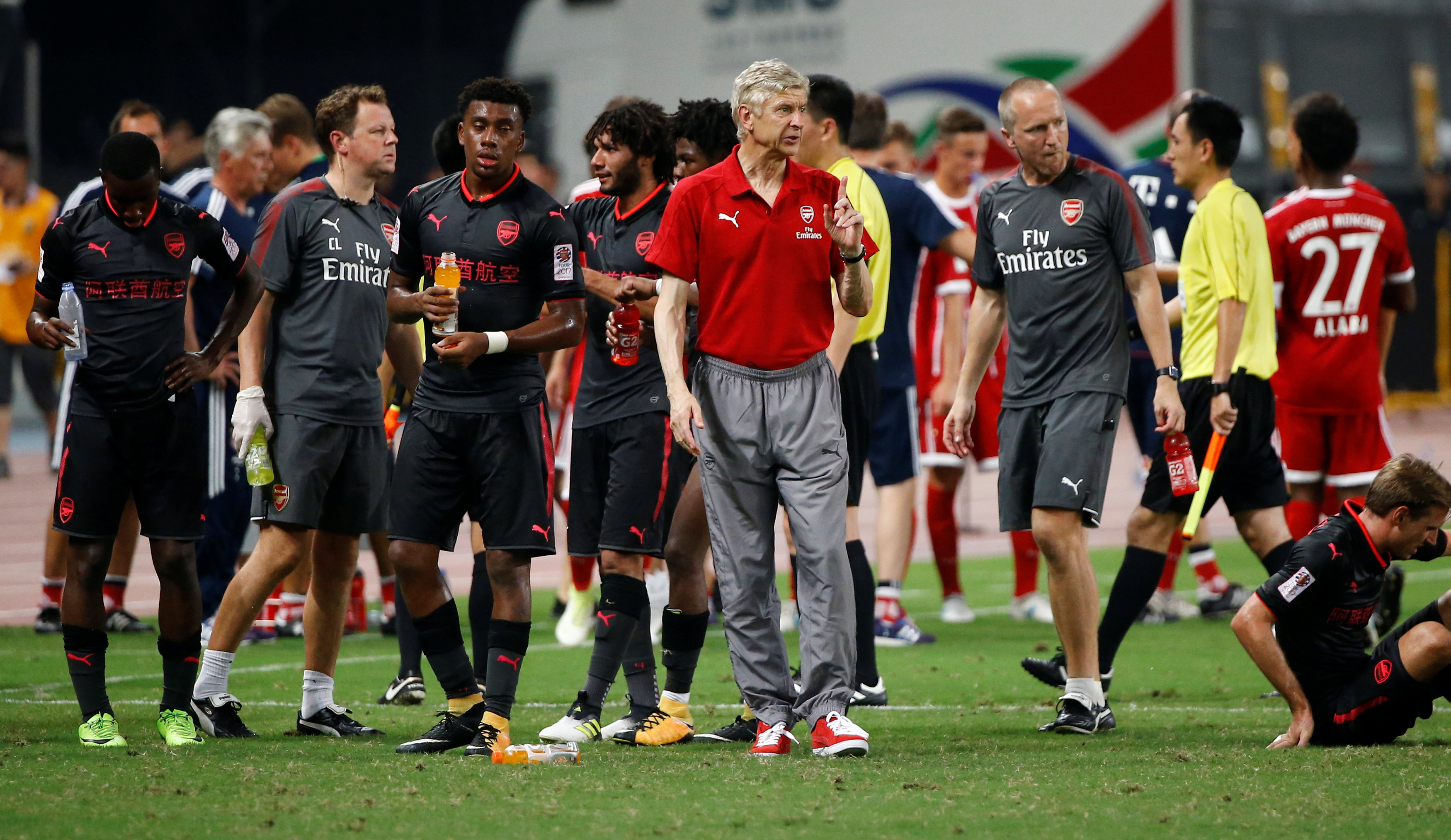 HLV Wenger (áo đỏ) khổ sở vì vụ ngộ độ thực phẩm của đội nhà ở Trung Quốc. Ảnh: REUTERS