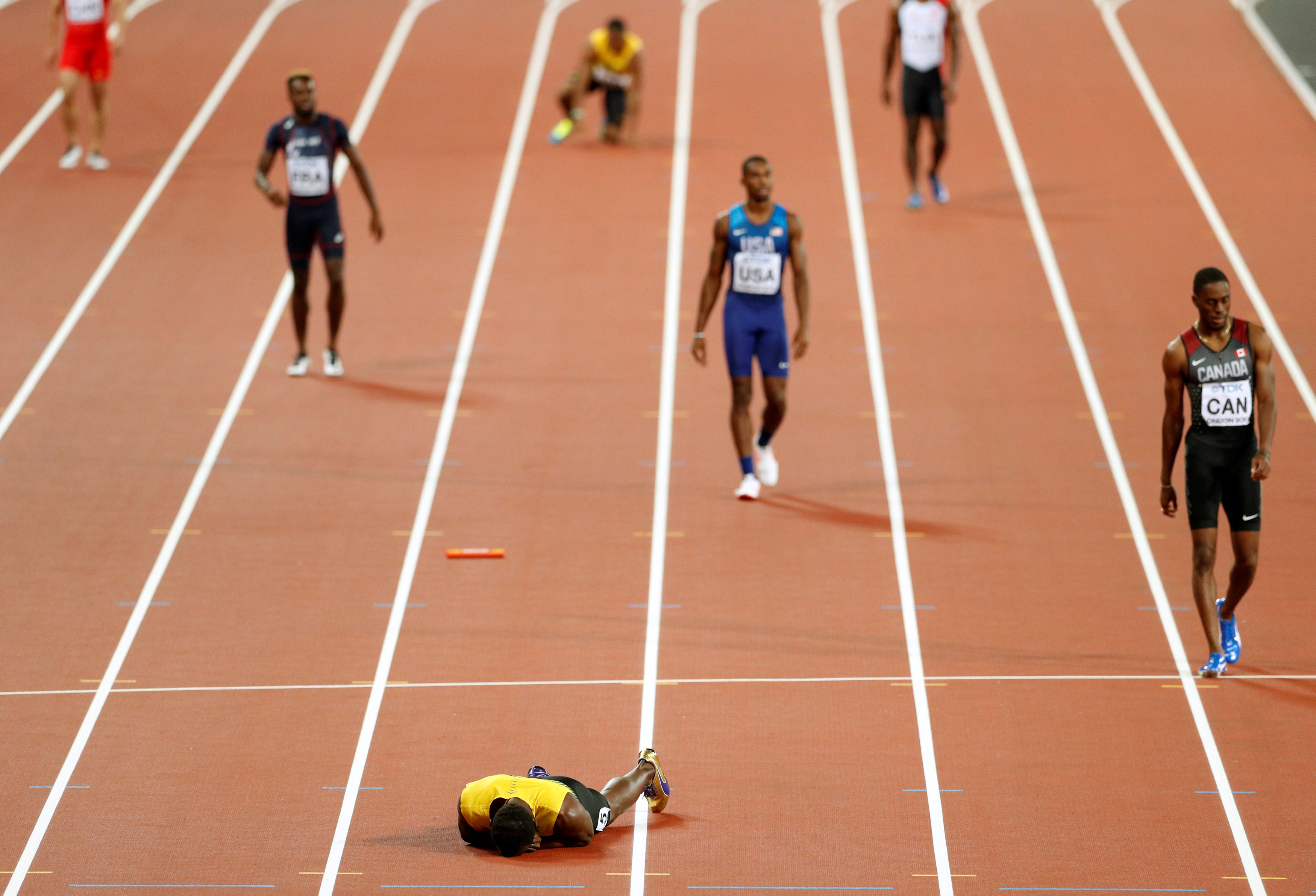 Bolt nằm xuống sân, ôm mặt. Một kết thúc không thể buồn hơn cho VĐV người Jamaica. Ảnh: REUTERS
