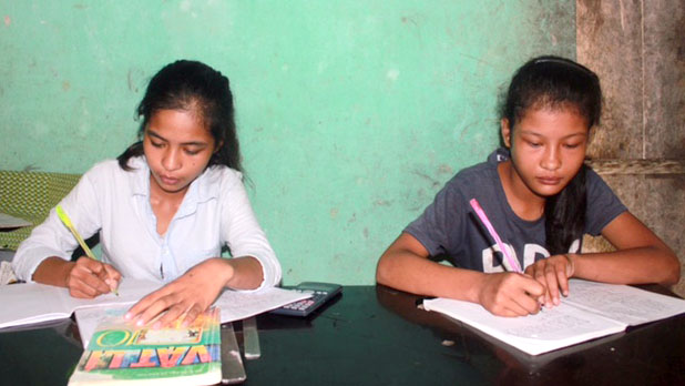 Hai chị em Lê Thị Thủy, Lê Thị Tình bên bàn học hàng ngày, quyết tâm học tập tốt để luôn đạt học sinh giỏi toàn diện - Ảnh: HÀ ĐỒNG