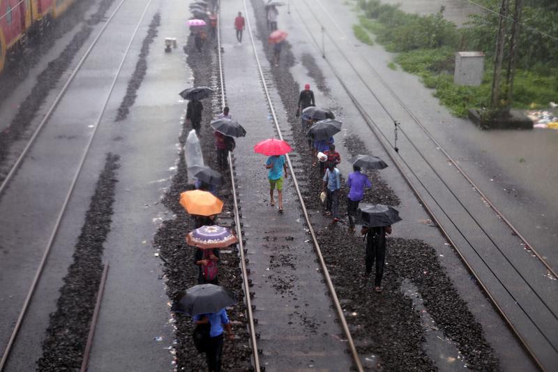 Người dân đi dọc một đường ray ngập nước ở Mumbai - Ảnh: Reuters